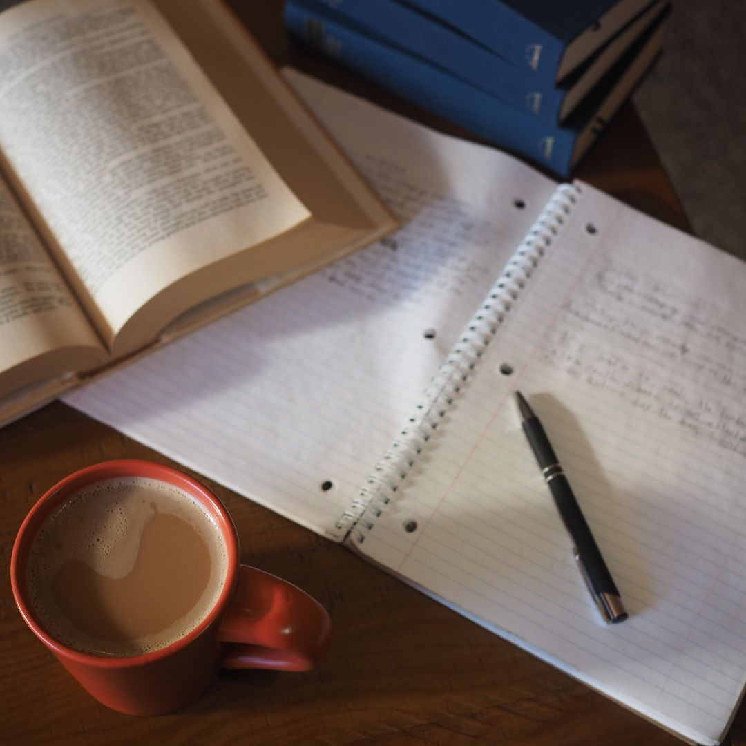 Notebook, open book, coffee cup on desk