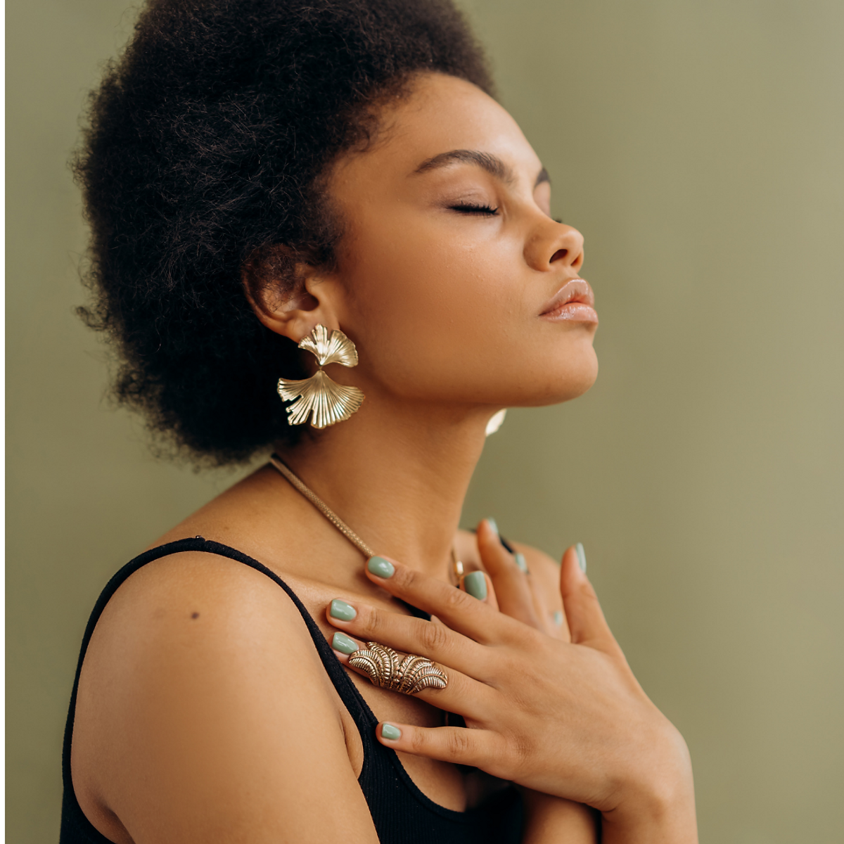 Woman wearing gold jewelry with closed eyes
