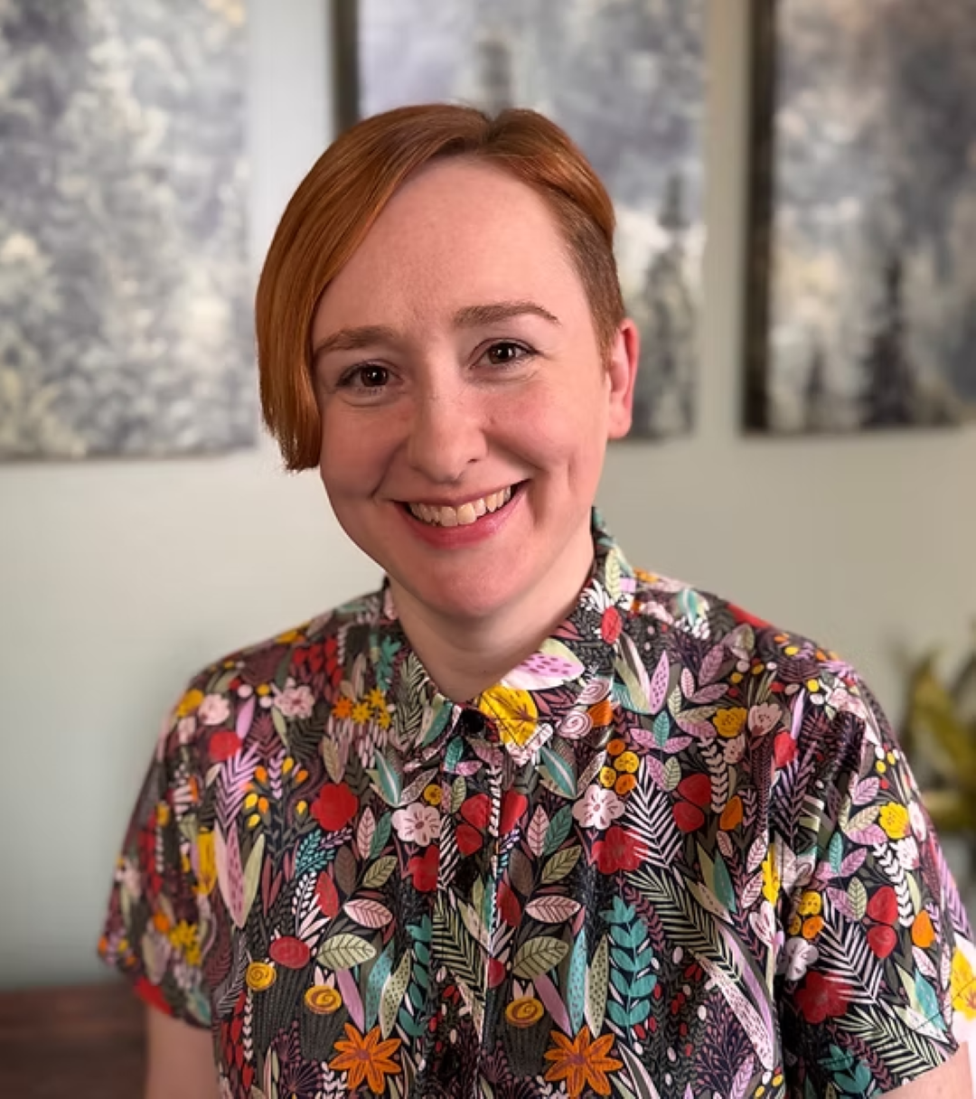 Smiling person in colorful floral shirt indoors.