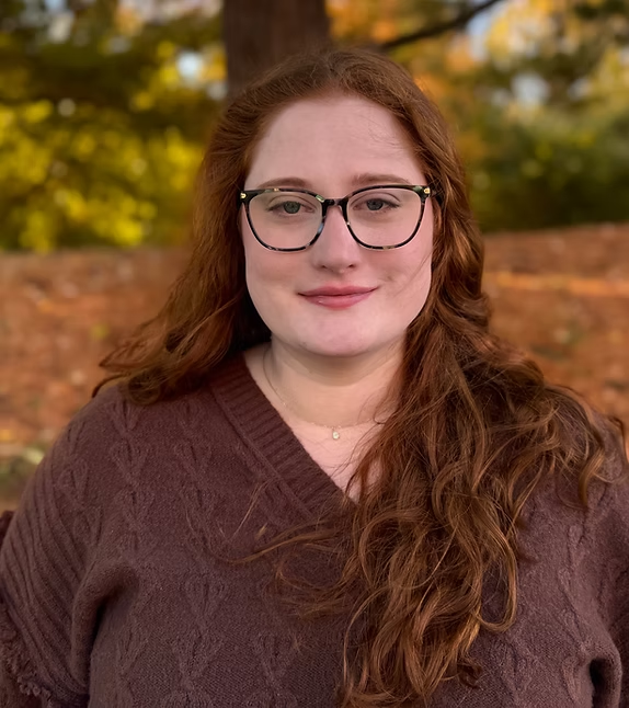 Woman outdoors in autumn scenery, wearing glasses.