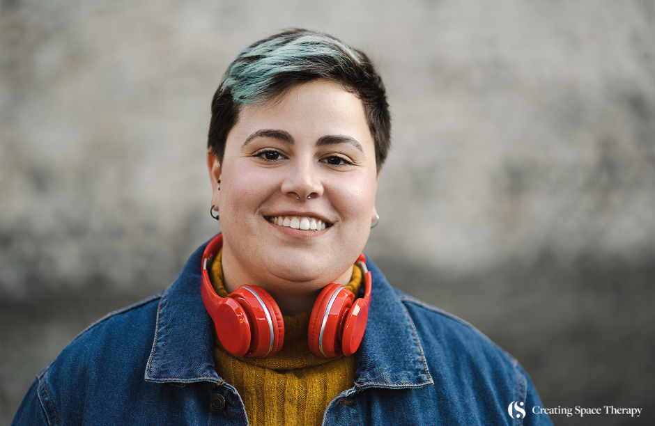 Person smiling with headphones and denim jacket.