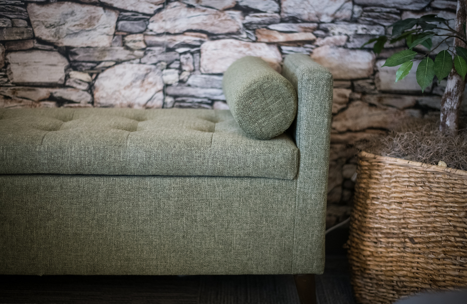 Green sofa near stone wall and plant basket