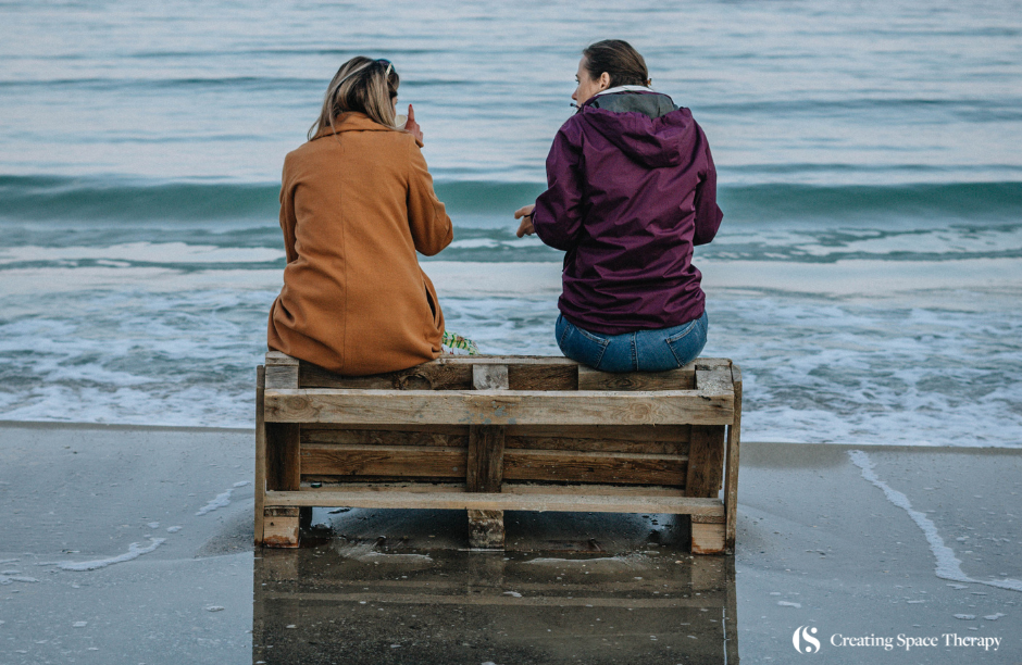 Two people sitting on a beach bench